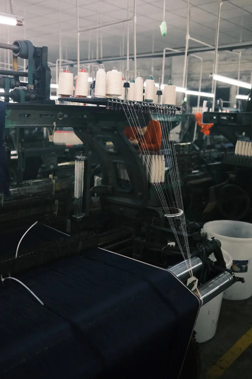 Factory Denim textile production equipment and yarn threads inside a working weaving workshop
