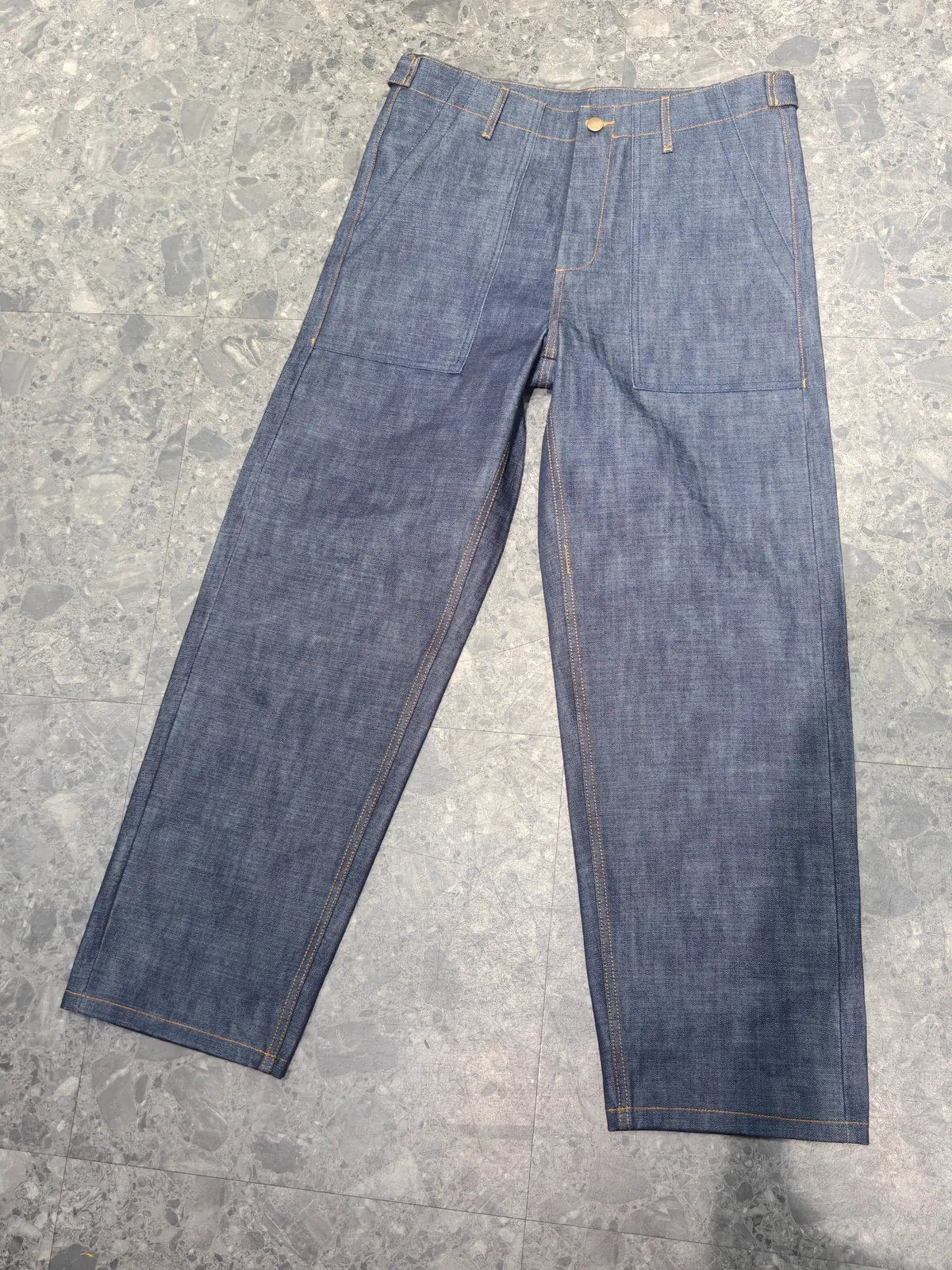 Front of straight-leg indigo denim trousers with large patch pockets and contrast stitching