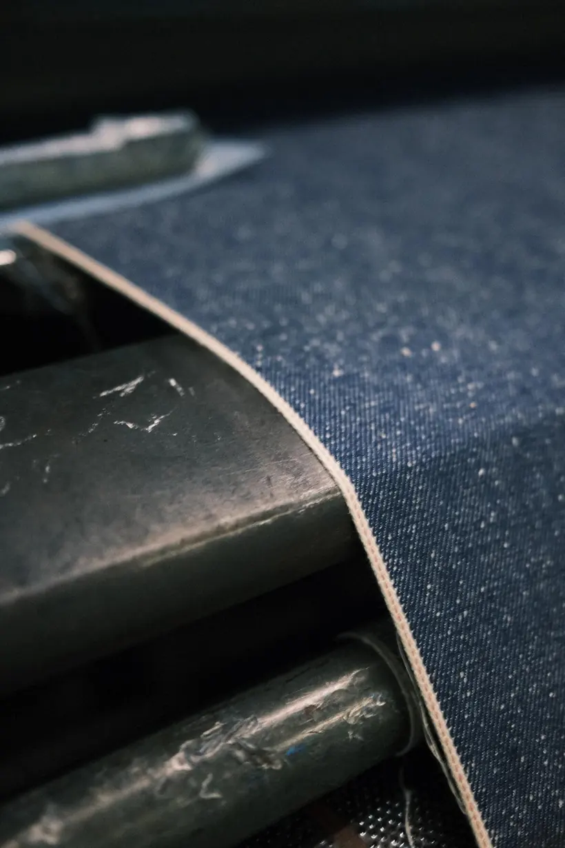 Close-up of a cream selvedge edge on indigo denim fabric during weaving